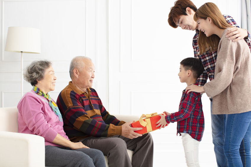 grandchild with parents giving a gift to grandparents